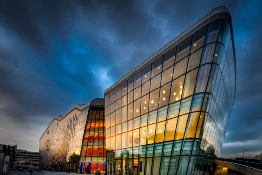 Exterior photo of the congress centre in Krakow at dusk with the sun reflecting off the glass exterior.